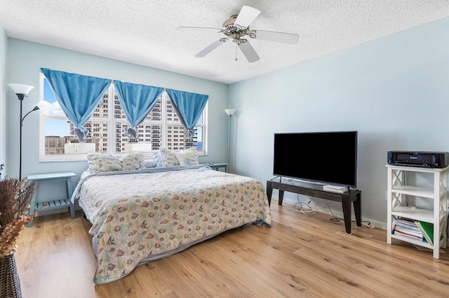 bedroom featuring ceiling fan, a textured ceiling, light hardwood / wood-style flooring, and multiple windows