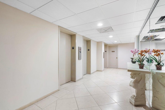 hallway with light tile patterned floors, elevator, and a paneled ceiling