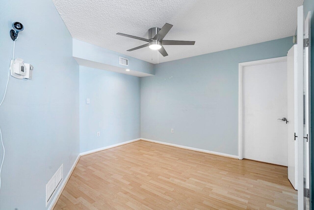 spare room featuring ceiling fan, light hardwood / wood-style floors, and a textured ceiling