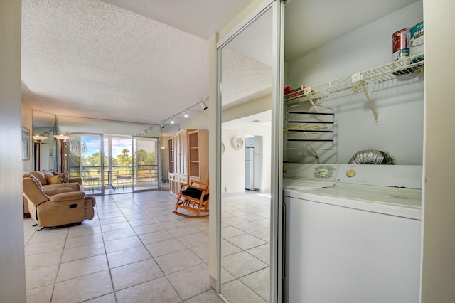 laundry room with track lighting, washer and clothes dryer, a textured ceiling, and light tile patterned floors