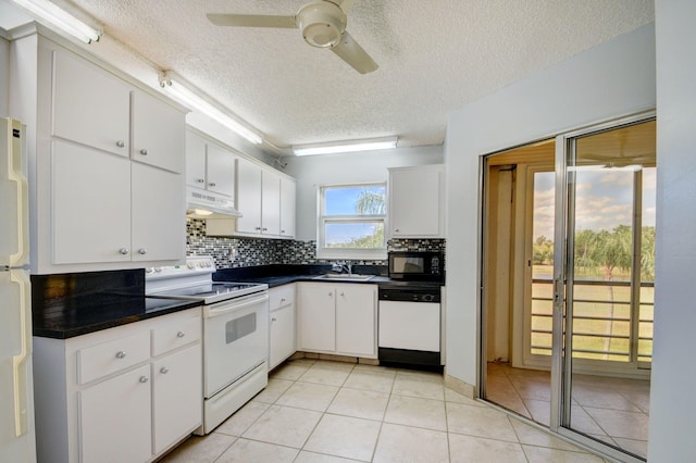 kitchen featuring white cabinetry, sink, backsplash, light tile patterned floors, and white appliances