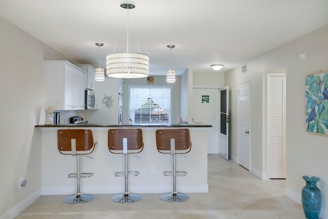 kitchen with white cabinetry, a breakfast bar area, kitchen peninsula, and pendant lighting