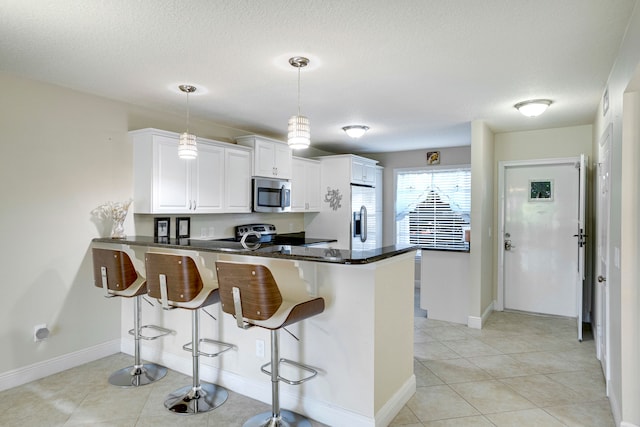 kitchen with kitchen peninsula, stainless steel appliances, pendant lighting, and light tile patterned flooring