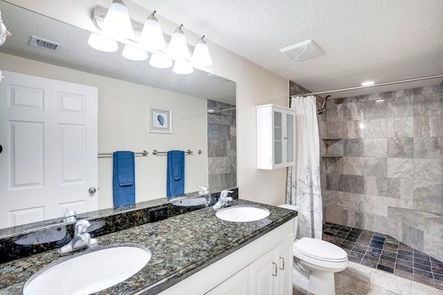 bathroom featuring tile patterned floors, double vanity, a textured ceiling, toilet, and walk in shower