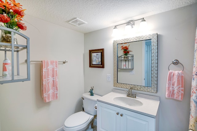 bathroom featuring a textured ceiling, vanity, and toilet