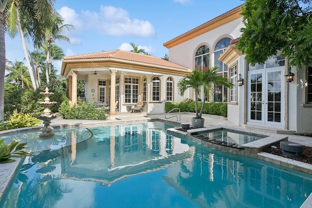 view of swimming pool featuring a pool with connected hot tub, french doors, a ceiling fan, and a patio