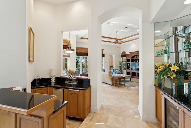 kitchen with light tile patterned floors, a raised ceiling, wine cooler, ceiling fan, and a towering ceiling