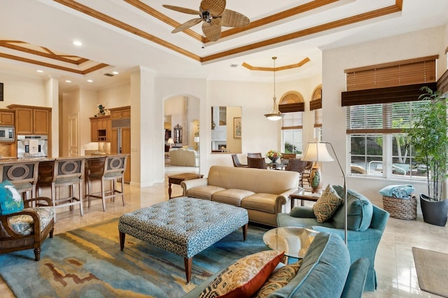 living room with ceiling fan, ornamental molding, light tile patterned floors, and a tray ceiling