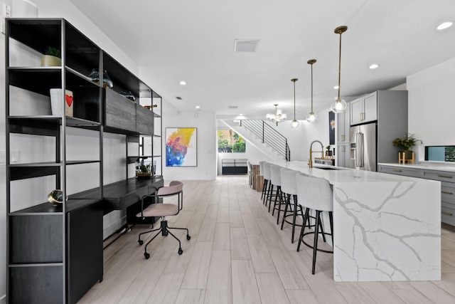 kitchen featuring an inviting chandelier, high end refrigerator, sink, and light hardwood / wood-style flooring