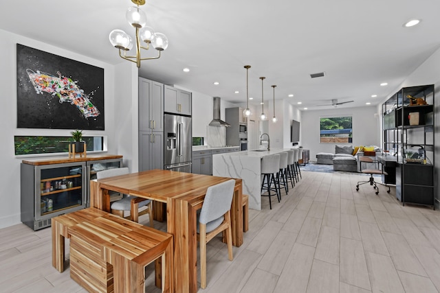 dining area with light hardwood / wood-style floors, ceiling fan with notable chandelier, and sink