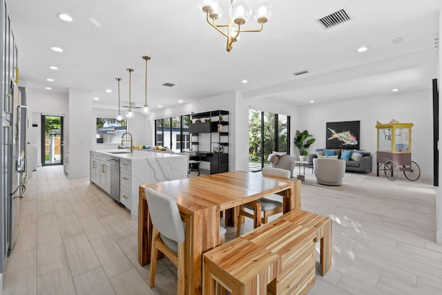 dining area featuring a chandelier, sink, and light hardwood / wood-style flooring