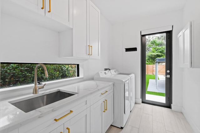 washroom with cabinets, sink, and independent washer and dryer