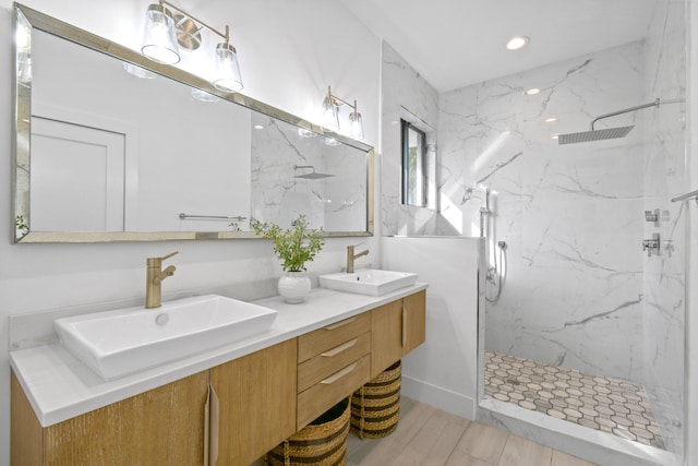 bathroom with hardwood / wood-style floors, vanity, and a tile shower