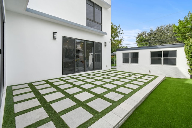 rear view of property featuring a lawn and a patio area