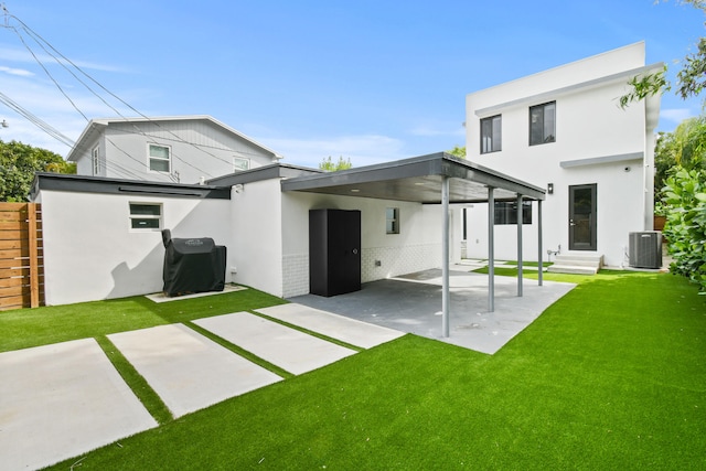 back of house featuring central AC unit, a lawn, and a carport