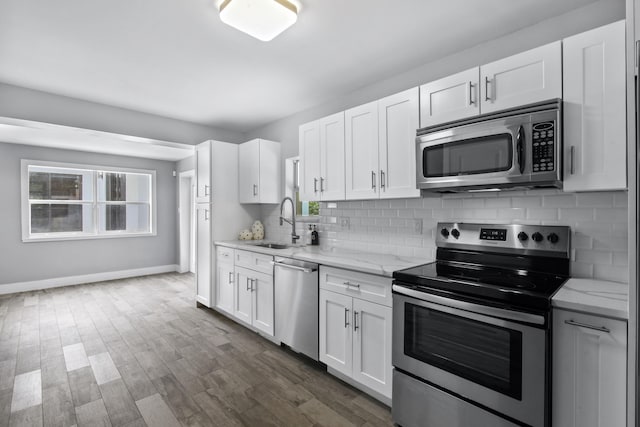 kitchen featuring stainless steel appliances, dark hardwood / wood-style flooring, light stone counters, white cabinets, and sink