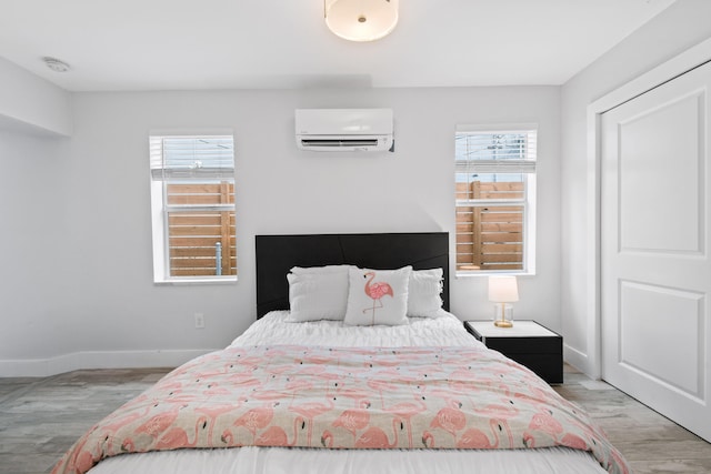 bedroom featuring light hardwood / wood-style floors, a wall mounted AC, and multiple windows