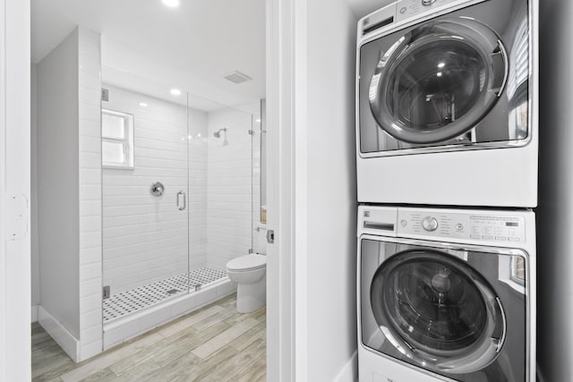 laundry area featuring stacked washing maching and dryer and light hardwood / wood-style flooring