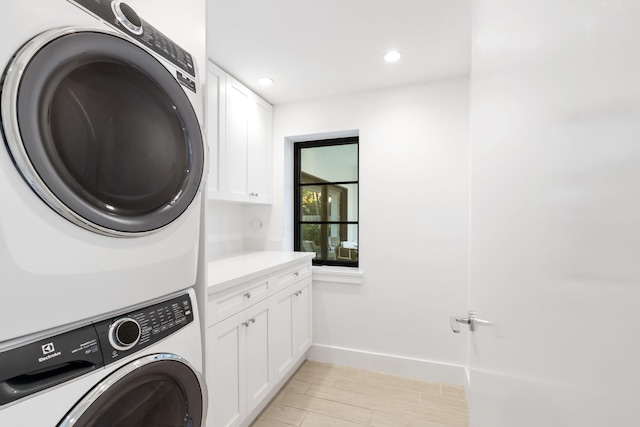 washroom with cabinets and stacked washer / dryer