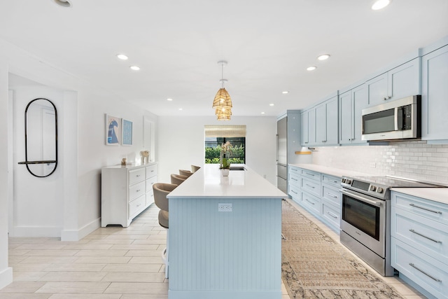 kitchen with a kitchen island, appliances with stainless steel finishes, pendant lighting, sink, and backsplash