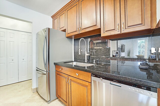 kitchen featuring backsplash, appliances with stainless steel finishes, light tile patterned floors, sink, and dark stone countertops