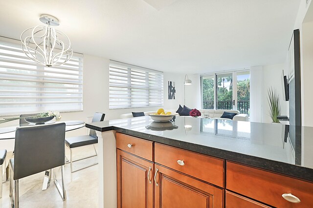 kitchen featuring dark stone counters, pendant lighting, a chandelier, and light tile patterned floors