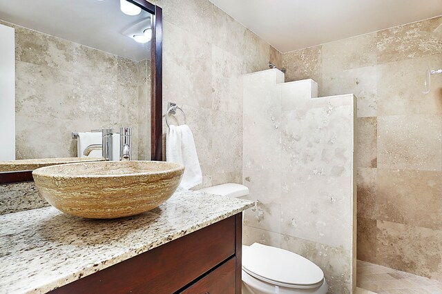 bathroom featuring tile walls, toilet, vanity, and tiled shower