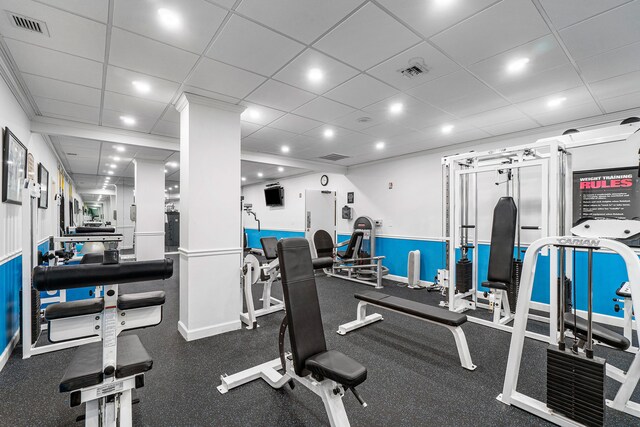 workout area featuring decorative columns and a paneled ceiling