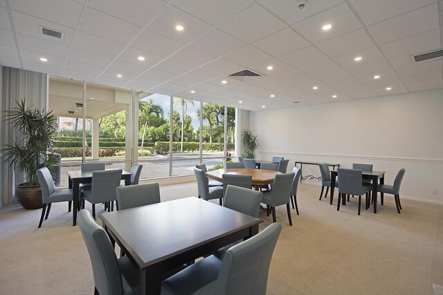 dining room with a wall of windows, a paneled ceiling, and light carpet