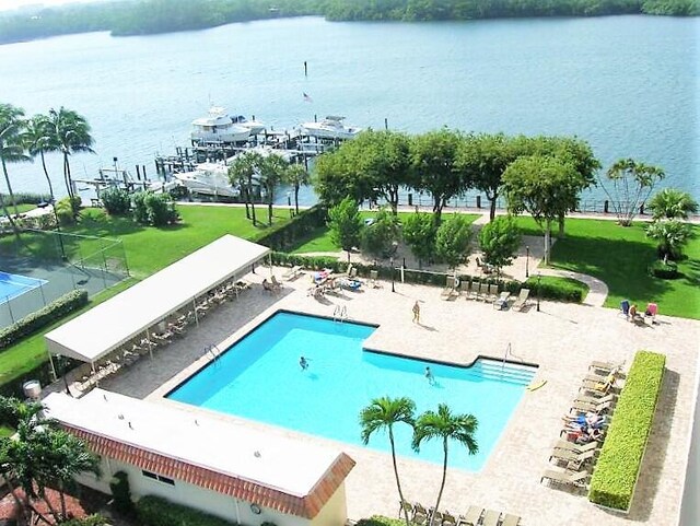 view of pool featuring a lawn, a patio area, and a water view