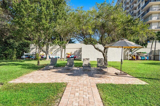 view of community featuring a lawn and a patio area