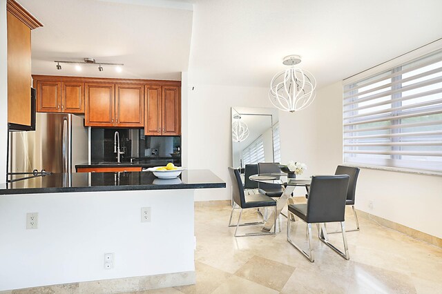 kitchen featuring track lighting, light tile patterned floors, decorative light fixtures, an inviting chandelier, and stainless steel fridge