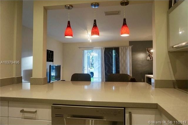 kitchen with dishwashing machine, hanging light fixtures, and white cabinets