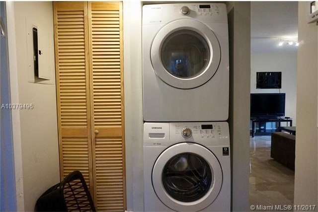 clothes washing area featuring parquet floors and stacked washing maching and dryer