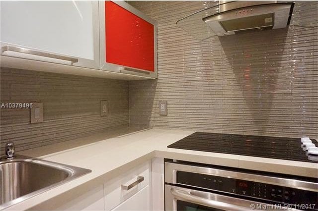 kitchen featuring backsplash, oven, sink, and white cabinets