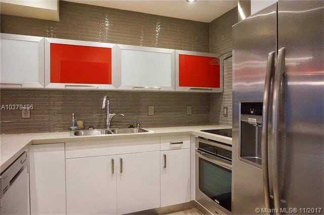 kitchen featuring stainless steel appliances, white cabinetry, sink, and backsplash