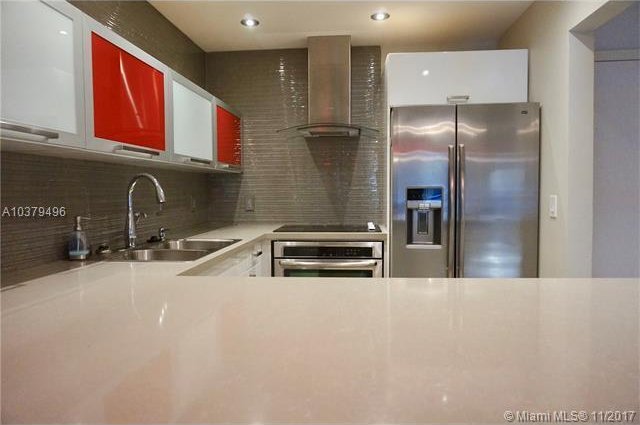 kitchen with wall chimney exhaust hood, stainless steel appliances, sink, and decorative backsplash