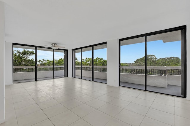 tiled empty room with a wealth of natural light, floor to ceiling windows, and ceiling fan