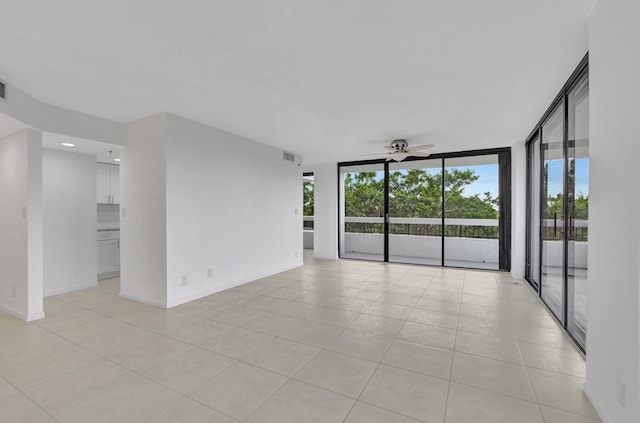 tiled empty room with a healthy amount of sunlight, ceiling fan, and expansive windows