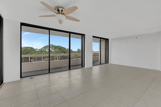 spare room featuring light tile patterned flooring, ceiling fan, and a wall of windows