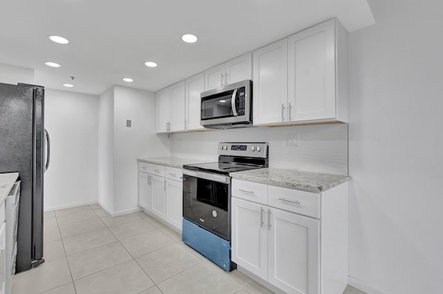 kitchen with light tile patterned floors, light stone counters, stainless steel appliances, and white cabinetry