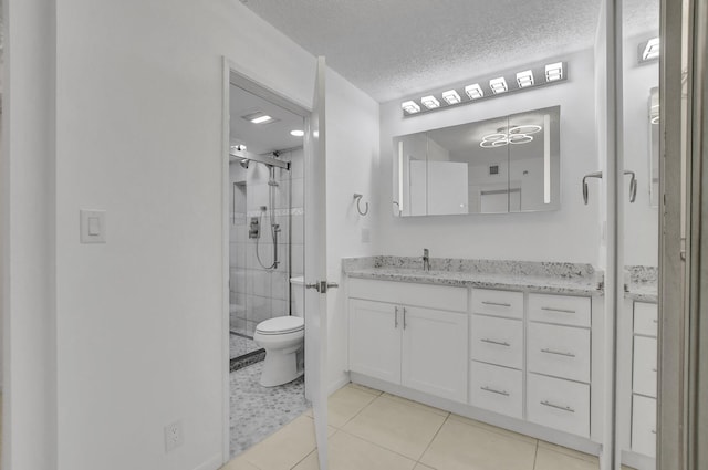 bathroom featuring a shower with door, vanity, a textured ceiling, tile patterned flooring, and toilet