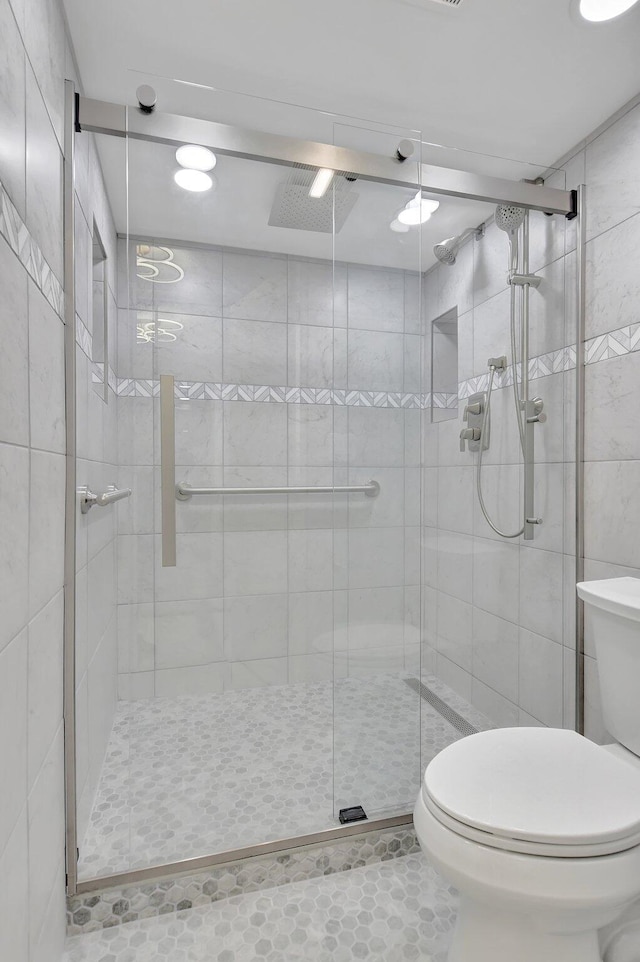 bathroom with toilet, an enclosed shower, and tile patterned floors