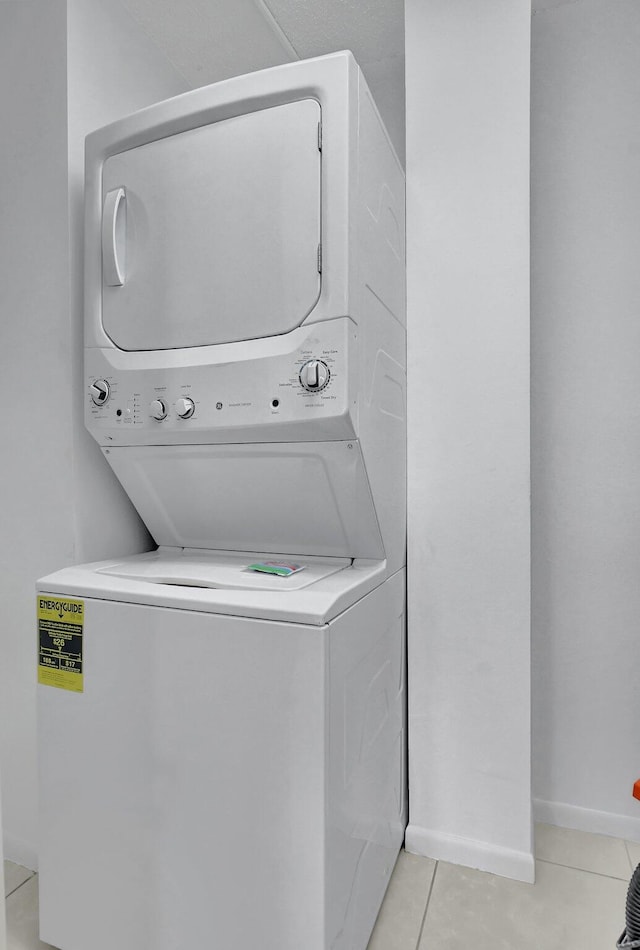 clothes washing area featuring stacked washing maching and dryer and light tile patterned flooring