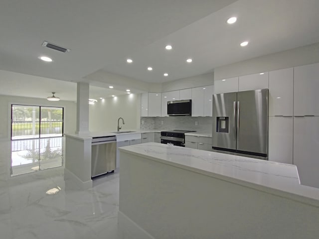 kitchen featuring tasteful backsplash, stainless steel appliances, sink, light stone countertops, and white cabinets