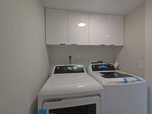 clothes washing area with cabinets and washer and clothes dryer