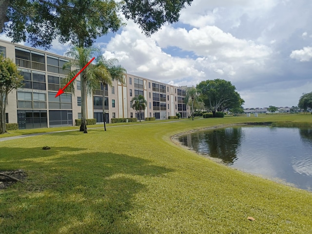 view of home's community with a water view and a lawn