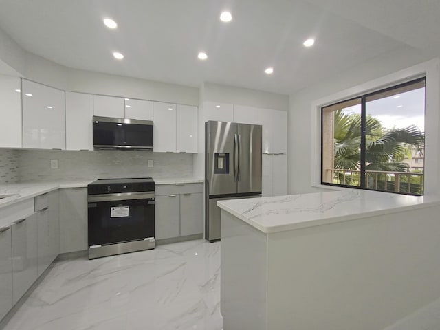 kitchen featuring tasteful backsplash, light stone counters, stainless steel appliances, and white cabinetry