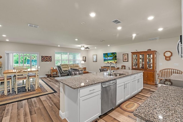 kitchen featuring white cabinetry, a kitchen island with sink, light stone countertops, sink, and stainless steel dishwasher