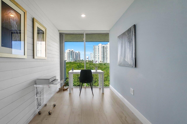 unfurnished office featuring baseboards, floor to ceiling windows, wood finished floors, recessed lighting, and a view of city